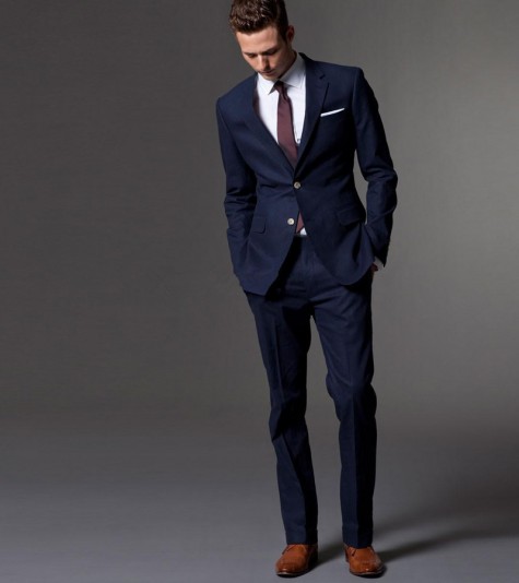 Người đàn ông mặc suit nam xanh navy phối cà vạt đỏ mận, khăn túi trắng và giày da nâu theo phong cách lịch lãm