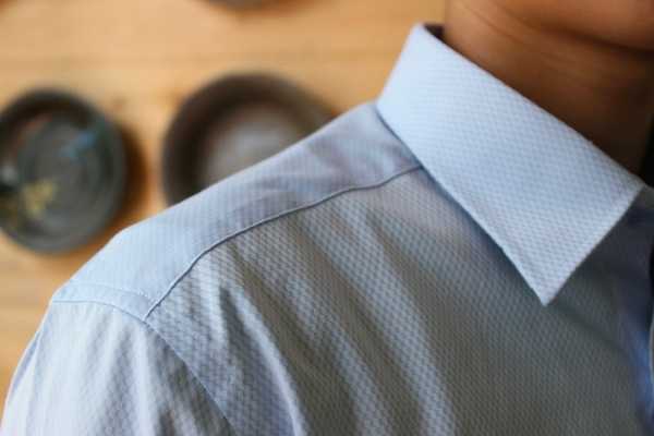 Cận cảnh vai và cổ áo sơ mi nam màu xanh kháng nhăn, đường vai phẳng phiu khi đang mặc